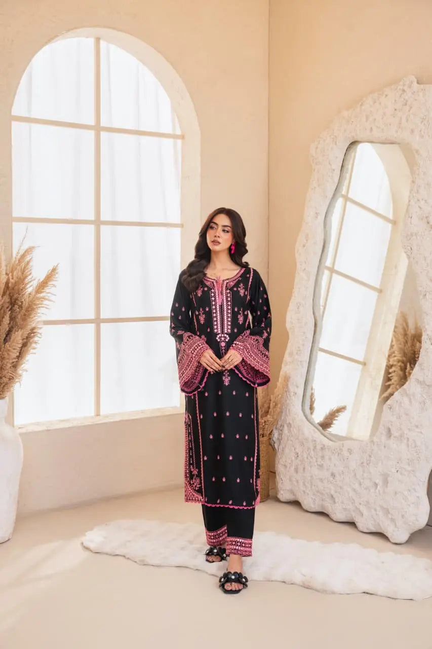 Woman in a black and pink traditional outfit standing in a room with a large mirror and decorative elements.