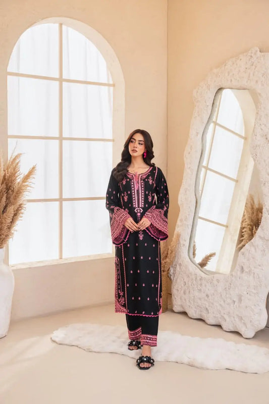 Woman in a black and pink traditional outfit standing in a room with a large mirror and decorative elements.