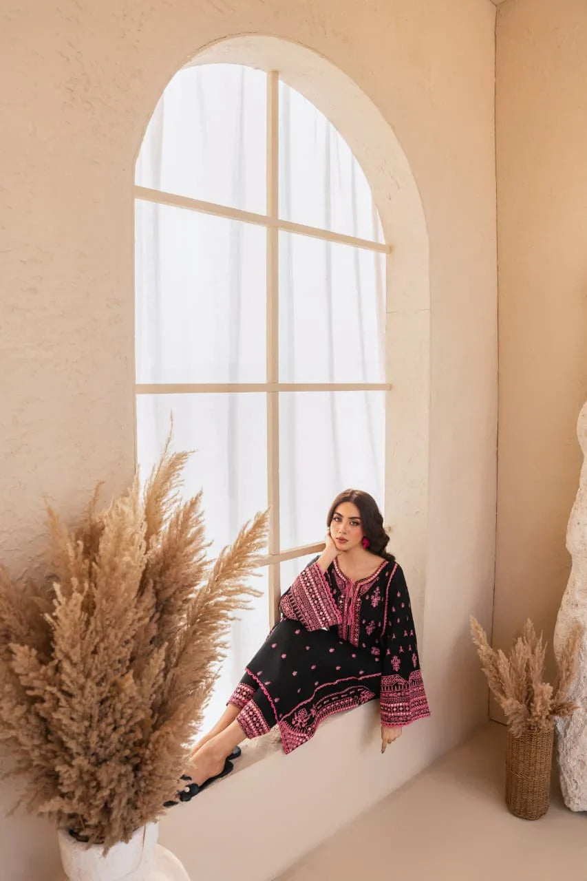 Woman sitting by a large arched window with decorative plants around her.