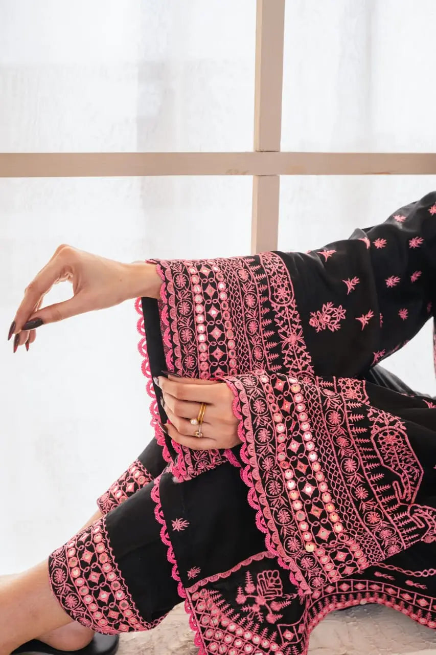 Person wearing a black and pink embroidered outfit with a blurred background